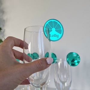 May include: Teal blue glass drink markers with a lime slice design and the name "Lolly" printed on one of the markers.