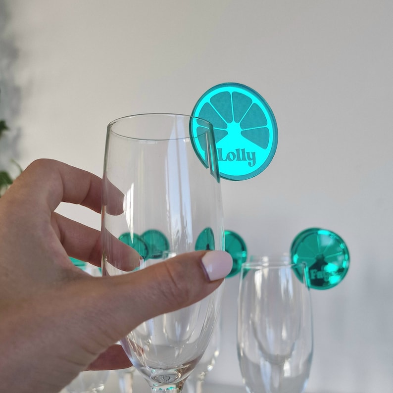 May include: Teal blue glass drink markers with a lime slice design and the name "Lolly" printed on one of the markers.