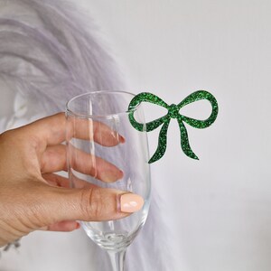 Peut inclure: Une fl&ucirc;te &agrave; champagne en verre transparent avec un n&oelig;ud en paillettes vertes attach&eacute; au bord.