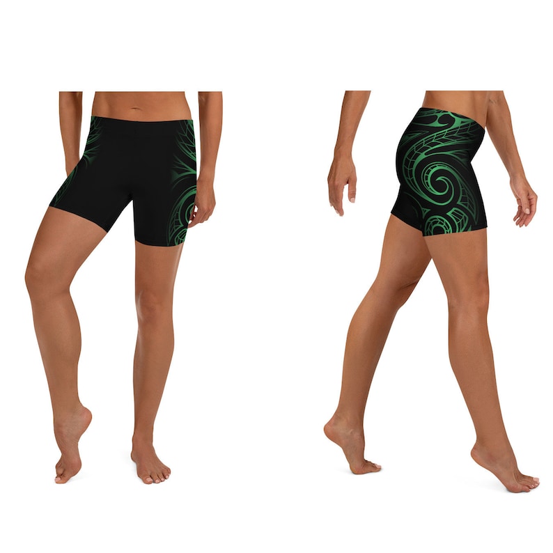 May include: Black athletic shorts with a green tribal design on the sides. The shorts are made of a stretchy material and are designed for workouts or casual wear. The shorts are shown on a person.