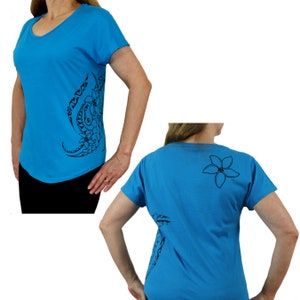 May include: A turquoise blue t-shirt with a black floral design on the side. The back of the shirt has a single black flower design.