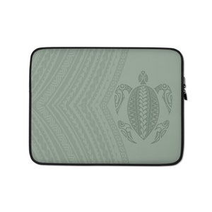 May include: A sage green laptop sleeve with a tribal turtle design. The sleeve has a black border and a zip closure. The turtle is centered on the right, with a detailed pattern. The left side has a repeating geometric pattern.