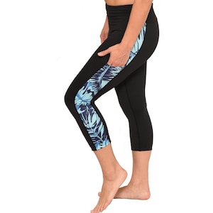 May include: Black capri leggings with a blue and white floral print on the side. The leggings have a high waist and a fitted silhouette.