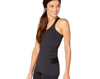 May include: Black athletic vest top with a V-neck and mesh panels on the side. The vest has a single strap on one shoulder and is paired with black leggings. The style is sporty and suitable for workouts or the gym.