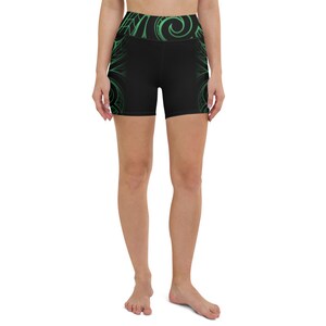 May include: Black yoga shorts with a high waistband and a green, swirling design. The shorts feature a geometric pattern along the sides and waistband. The shorts are made of a stretchy material.