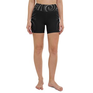 May include: Black yoga shorts with a high waistband and a decorative gray pattern. The shorts feature a repeating design on the sides and waistband. The shorts are made of a stretchy material.