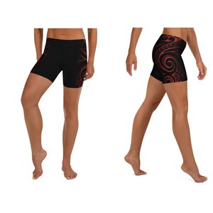 May include: Black athletic shorts with a red tribal design. The shorts are form-fitting and reach mid-thigh. The tribal design is on the side of the shorts.