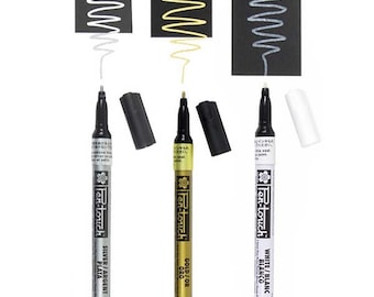 Pode incluir: Três marcadores de tinta metálica com tampas pretas e etiquetas brancas. Os marcadores são etiquetados "Ten-touch" e têm as cores dourado, prateado e branco.