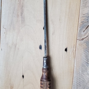 May include: A vintage screwdriver with a wooden handle and a metal shaft. The handle is brown and has a grooved pattern. The shaft is silver and has a flat head.
