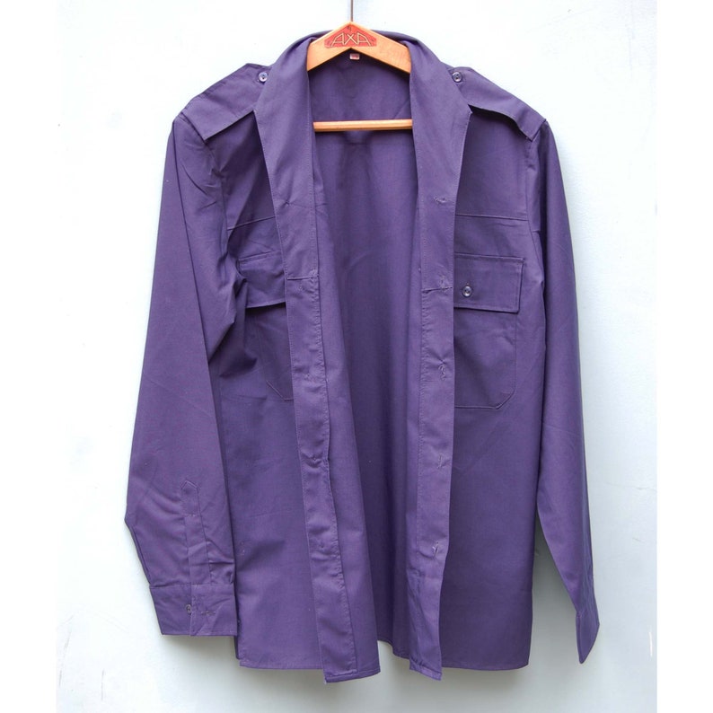 May include: A long-sleeved, purple button-down shirt with two chest pockets and a button-up collar.