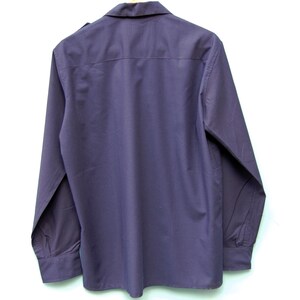 May include: A long-sleeved, dark purple button-down shirt with a collared neckline.