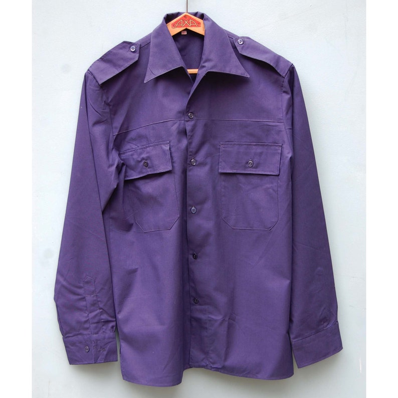 May include: A long-sleeved, purple button-down shirt with two chest pockets and a collared neckline.