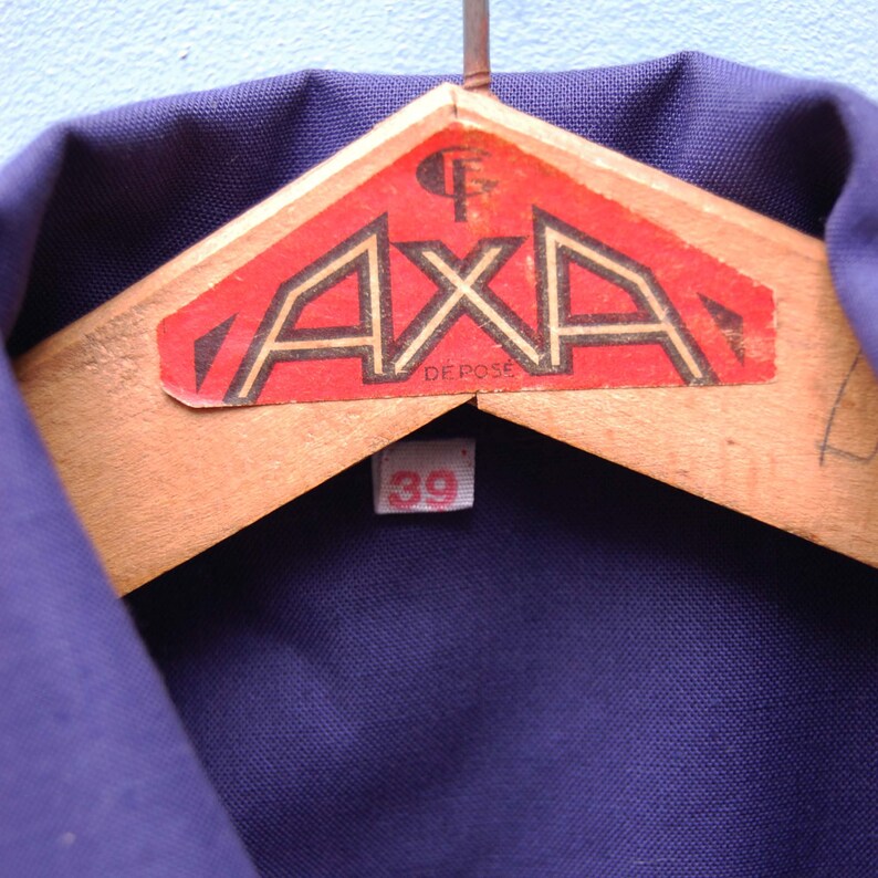 May include: A dark blue work shirt with a red and white label that says "AXA DEPOSE" and a white size tag that says "39".