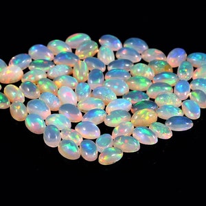 Puede incluir: Una colecci&oacute;n de piedras preciosas de &oacute;palo de forma ovalada e iridiscente. Los &oacute;palos son de color blanco p&aacute;lido con destellos de azul, verde y amarillo.