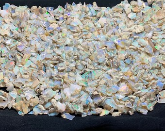 May include: A large pile of white opal rough, with iridescent flashes of colour. The opal pieces are various shapes and sizes.