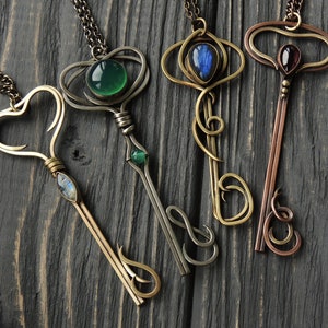 May include: Four ornate key-shaped necklaces with different colored gemstones. The necklaces are made of silver and brass and feature intricate designs.