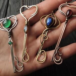May include: Four ornate key-shaped pendants with different colored gemstones. The pendants are made of silver, brass, and copper.