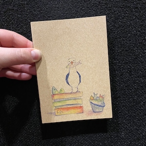 May include: A hand-drawn illustration of a seagull holding a fish in its beak, standing on a stack of books with the word "fish" written on the bottom book. A bucket with fish inside sits next to the books.
