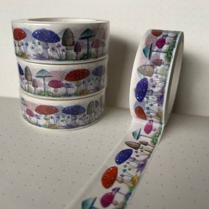 Könnte beinhalten: Vier Rollen Washi-Tape mit einem Pilz-Design. Das Band ist weiß mit Aquarell-Illustrationen von Pilzen in Rot-, Lila- und Brauntönen.