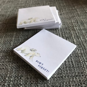 May include: A stack of white sticky note pads with a watercolour illustration of a polar bear and two cubs. The text "Don't Forget!" is printed in blue below the illustration.