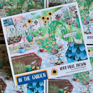 May include: A 1000 piece jigsaw puzzle titled "In the Garden" by Catherine Redgate. The puzzle features a colorful illustration of a garden with a greenhouse, flowers, vegetables, and a chicken coop. The puzzle is made with recycled board and printed with vegan ink.