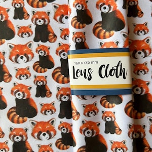 May include: White lens cloth with a repeating pattern of red pandas in orange and black. The cloth has a blue and yellow label that reads "Lens Cloth" and measures 150 x 180 mm.