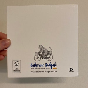 Puede incluir: Una tarjeta blanca con una ilustraci&oacute;n en blanco y negro de un oso montando una bicicleta con un conejo en la cesta. La tarjeta tiene el texto "Catherine Redgate" y "Artist | Illustrator | Designer | Writer" y la direcci&oacute;n del sitio web "www.catherine-redgate.co.uk". La tarjeta tambi&eacute;n tiene el logotipo de FSC y el texto "RECYCLABLE".