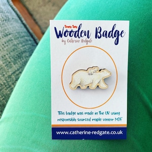 Könnte beinhalten: Ein Holzbadge mit einem weißen Eisbären mit einem Jungtier auf dem Rücken. Das Badge ist in Großbritannien aus verantwortungsvoll gewonnenem Ahornfurnier MDF hergestellt. Der Text "Teeny Tiny Wooden Badge by Catherine Redgale" ist auf der Karte gedruckt.