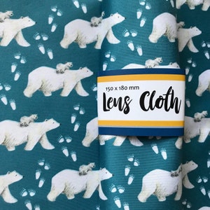 May include: A teal blue lens cloth with a repeating pattern of white polar bears and paw prints. The cloth has a label that reads "150 x 180 mm Lens Cloth".