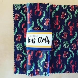 May include: A pair of black microfiber lens cleaning cloths with a red lobster and green seaweed pattern. The cloths are 150 x 180 mm and have the text "Lens Cloth" printed on them.