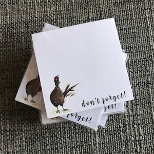 May include: A stack of notepads featuring a pheasant illustration and the text "don't forget!" on the front.