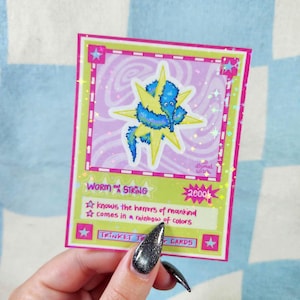 May include: A colorful trading card featuring a blue worm-like creature with a yellow starburst design. The card has a pink and green border with the text "WORM ON STRING" and "2000". Additional text includes "knows the horrors of mankind" and "comes in a rainbow of colors".