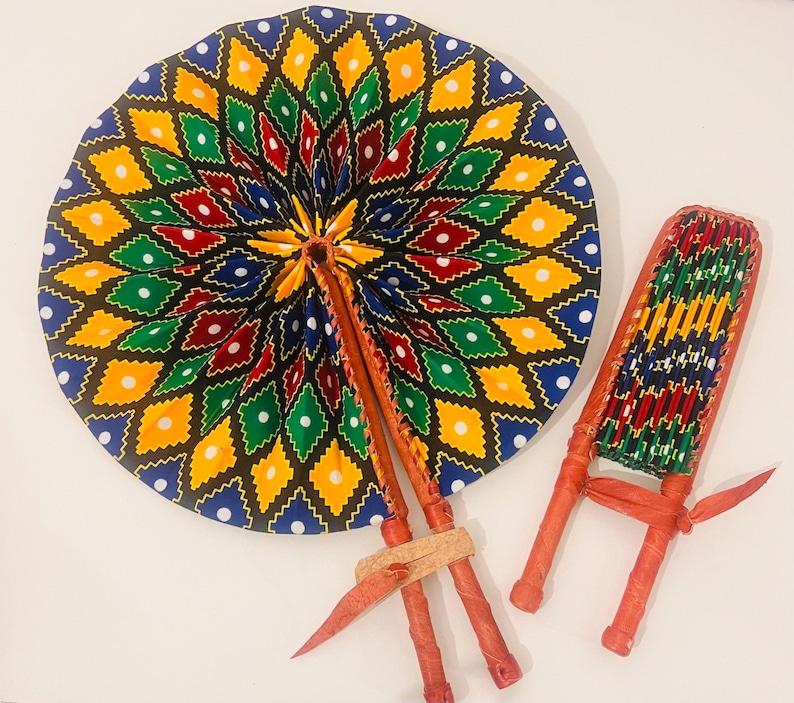 Pode incluir: Dois leques de m&atilde;o coloridos com um padr&atilde;o geom&eacute;trico de diamantes e pontos em tons de azul, verde, amarelo, vermelho e branco. Os leques s&atilde;o feitos de tecido e t&ecirc;m cabos de madeira.