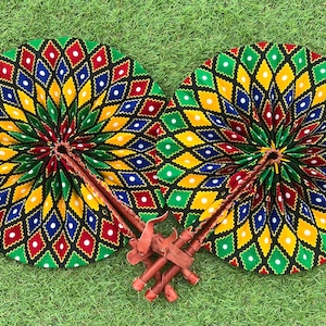 Pode incluir: Dois leques de m&atilde;o coloridos com fundo preto e um padr&atilde;o geom&eacute;trico de diamantes verdes, amarelos, vermelhos, azuis e brancos e pontos brancos. Os leques est&atilde;o dobrados e t&ecirc;m cabos de madeira.