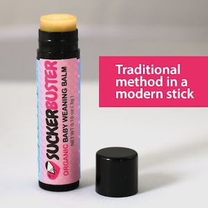 May include: A black and pink tube of organic baby weaning balm labeled "SUCKERBUSTER". The balm is in a stick form and is 0.10 oz (3g). The text "Traditional method in a modern stick" is written in pink on a white background.
