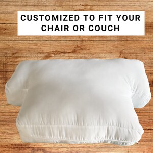 May include: White pillow with a zipper closure. The pillow is designed to fit a chair or couch. The text "CUSTOMIZED TO FIT YOUR CHAIR OR COUCH" is printed on a white rectangle above the pillow.