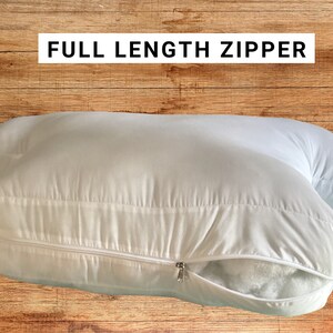 May include: A white body pillow with a full-length zipper. The zipper is open and the filling is visible.