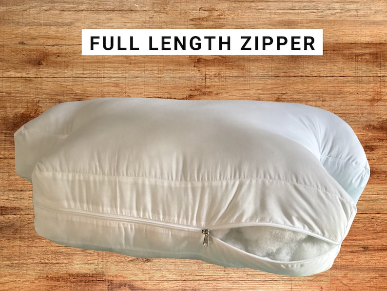 May include: A white body pillow with a full-length zipper. The zipper is open and the filling is visible.