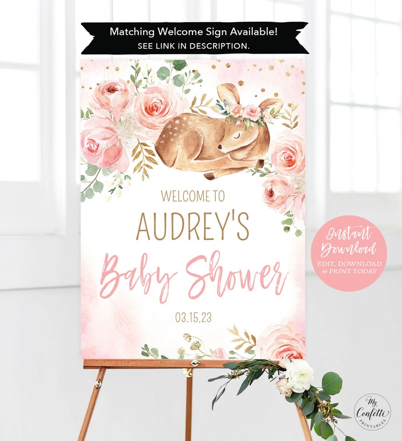 May include: A pink and gold baby shower welcome sign with a floral design and a sleeping fawn with a floral crown. The sign says "Welcome to Audrey's Baby Shower 03.15.23".