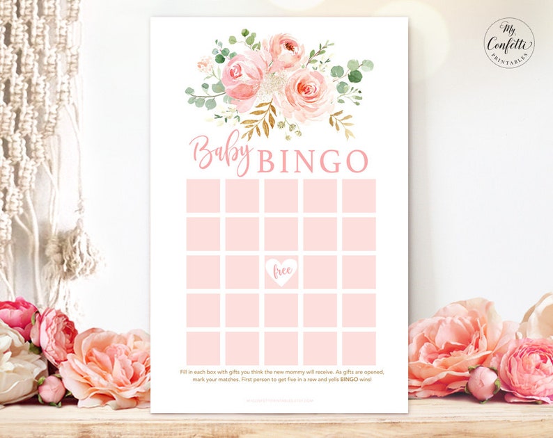 May include: A pink and white floral design with gold accents on a white background. The text "Baby Bingo" is in pink letters. The bingo card has 25 squares with a free space in the center. The text at the bottom reads "Fill in each box with gifts you think the new mommy will receive. As gifts are opened, mark your matches. First person to get five in a row and yell BINGO wins!"