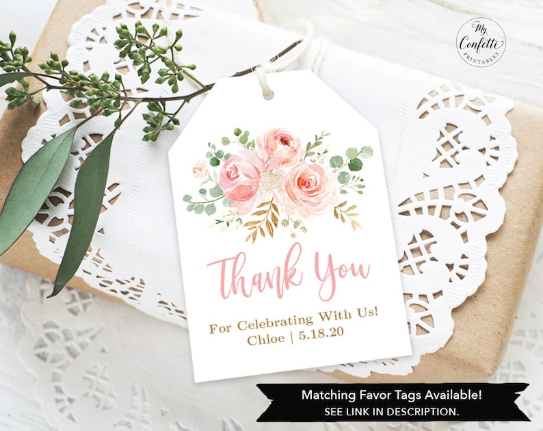 May include: A white gift tag with a floral design and the words "Thank You" in pink script. The tag also includes the text "For Celebrating With Us! Chloe 5.18.20". The tag is tied with twine and rests on a gift wrapped in brown paper.