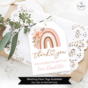 May include: A pink and brown rainbow with gold accents and floral details. The tag says "thank you" and "for celebrating with us! love, Charlotte". Matching favor tags are available.