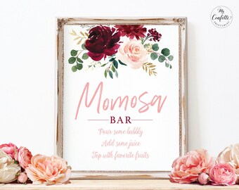 May include: A printable sign with a floral design in shades of burgundy and pink. The sign reads "Momosa Bar" and includes instructions for making mimosas: "Pour some bubbly, Add some juice, Top with favorite fruits".