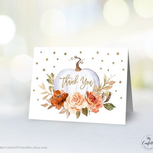 May include: White pumpkin with gold glitter and fall floral accents. The pumpkin has the words "Thank You" written on it.