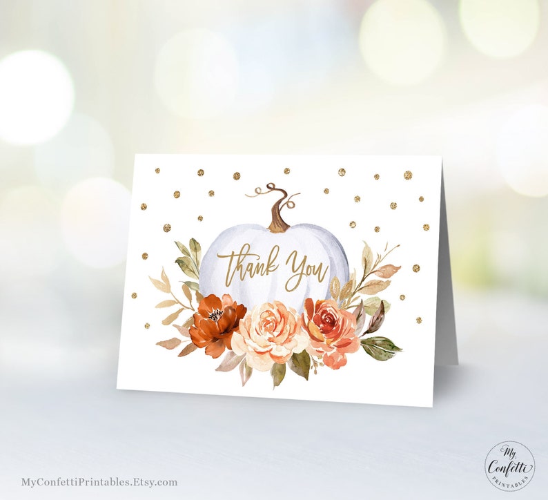 May include: White pumpkin with gold glitter and fall floral accents. The pumpkin has the words "Thank You" written on it.