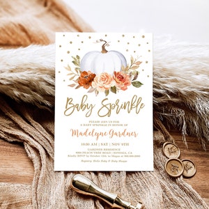 May include: A white pumpkin with orange and peach flowers and greenery. The text "Baby Sprinkle" is written in gold script. The text "Please join us for a baby sprinkle in honor of Madelyne Gardner" is written in gold. The date and time of the event are listed as "10:30 AM | SAT | NOV 9TH". The location is listed as "Gardner Residence 8993 Peach Tree Road Sonoma, CA". The RSVP information is listed as "Kindly RSVP by October 15th to Megan at 900.888.0000". The registry information is listed as "Registry: Hello Baby & Baby Shoppe".
