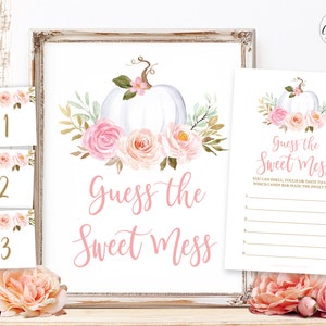 May include: A printable game card for a baby shower or party. The card features a white pumpkin with pink and peach flowers and greenery. The text on the card reads "Guess the Sweet Mess".