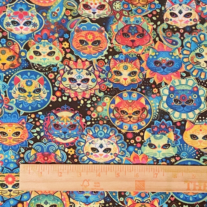 May include: A colorful fabric with a repeating pattern of sugar skull cats. The cats are wearing flowers and have intricate designs. The background is black with a paisley pattern.