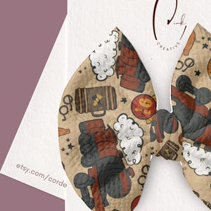 May include: A bow-shaped hair accessory featuring a tan background with a repeating pattern of red and black steam trains, white clouds of smoke, brown suitcases, round glasses, and red circular signs with the number nine and three quarters.