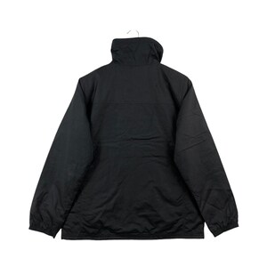 May include: A black jacket with a high collar, hanging from a white hook. The jacket has a simple design with a smooth, matte finish. The back view shows the full length of the jacket, with long sleeves and a straight hemline.